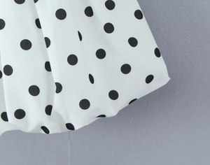 Gros plan sur l'imprimé à pois noirs sur tissu blanc fluide pour une robe de style français