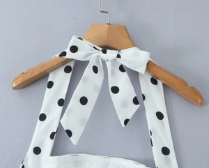 Gros plan d'une robe dos nu blanche à pois noirs avec un détail de nœud élégant