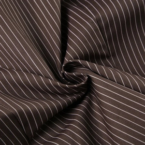 Detail of dark brown pinstripe cotton fabric with vertical white stripes and smooth texture