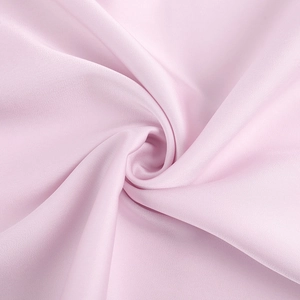 Gros plan sur un tissu rose clair brillant aux plis élégants et texture fine