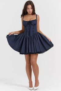 Detail of navy corset dress featuring black lace waist panel and pleated hem design