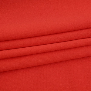 Vue macro du tissu en mousseline rouge montrant la texture fine et les plis de la robe