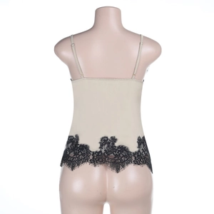 Detail of beige camisole back featuring delicate black floral lace trim at the hemline
