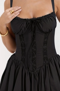 Detail of black corset dress featuring lace trim and lace-up bow on the bodice
