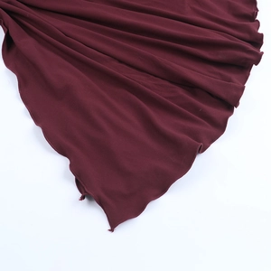 Detail of burgundy dress featuring soft knit fabric and asymmetrical wavy lettuce hem