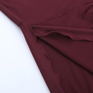 Close-up of wavy lettuce hem stitching on a deep wine red slim dress fabric