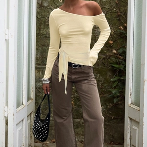 Détail du haut en tricot jaune clair avec col asymétrique et ceinture nouée à la taille
