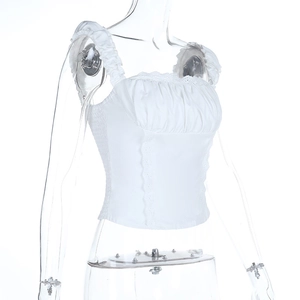 Detail of ruched white crop top featuring lace trim and ruffled shoulder straps
