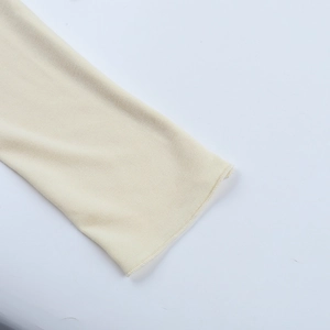 Gros plan détaillé sur les coutures du poignet d'un t-shirt beige à manches longues