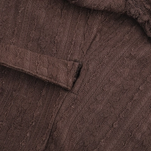 Gros plan sur tissu crêpe marron foncé avec détails noués et bordure en dentelle fine
