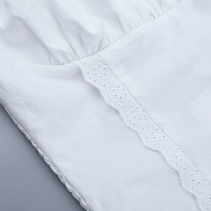 Detailed macro view of white T-shirt fabric featuring embroidered cutouts and pleated details