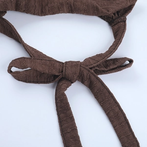 Détail du tissu texturé marron foncé avec un nœud fait main et un tissage doux au toucher