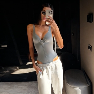 Detail of grey-green slim bodysuit featuring deep V-neck, zipper and ruched chest fabric