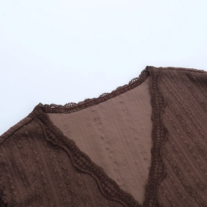 Détail du col en V avec bordure en dentelle et texture côtelée sur haut en maille marron