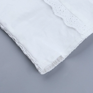 Detailed view of the white cotton top featuring hollow embroidery and elastic cuffs