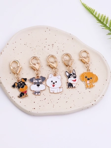 Detail of five enamel dog keychains with heart clasps displayed on a ceramic tray