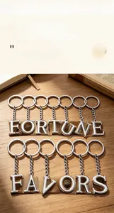 Polished silver alloy letter keychain featuring Fortune Favors text on a wooden desk