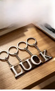Detailed close-up of polished metal LUCK letter keychains on a wooden desk surface