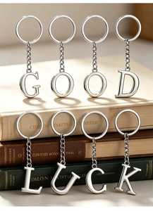Close-up of GOOD LUCK silver metal alphabet keychains arranged on vintage books