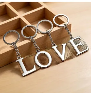 Detailed view of polished silver metal LOVE letter keychains on a natural wood surface