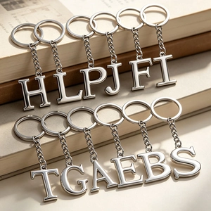 Polished silver metal alphabet keychains in serif font arranged on a vintage book