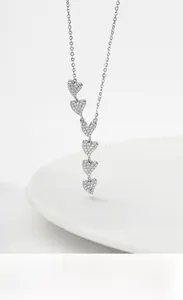 Macro detail of S925 sterling silver necklace with six vertical zircon heart pendants