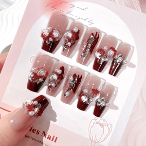 Macro shot of long coffin press-on nails with 3D roses, pearls, and crystals in burgundy