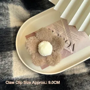 Gros plan d'une pince à cheveux fleur en peluche marron de 9 cm sur un plateau
