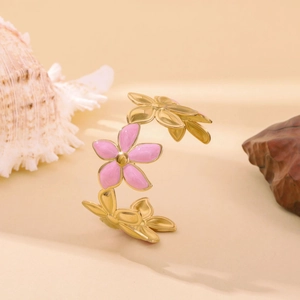 Golden stainless steel open bangle with pink enamel flowers on a natural stone base