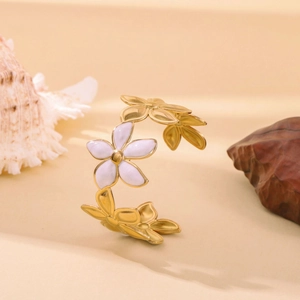 Detailed close-up of golden floral petal open bangle with white enamel inlay and stones