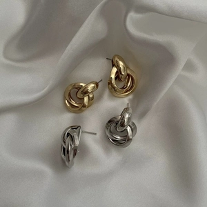 Close-up of interlocking gold and silver multi-circle earrings on white silk fabric