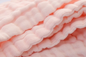 Detailed macro view of soft pink multi-layer muslin cotton fabric with bubble texture