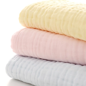Close-up of folded cotton muslin baby towels with soft honeycomb texture and pastel colors