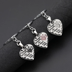 Macro view of memorial heart pendants with colored paw prints and engraved text on metal