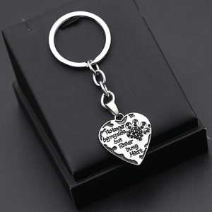 Silver pet memorial heart keychain with paw print and engraved emotional text on black box