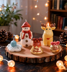 Close-up of handmade snowman, reindeer and bell candles on a rustic wooden base