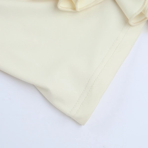 Détail de l'ourlet à volants et coutures de précision sur le haut licou dos nu crème