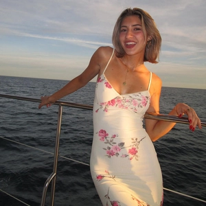 Detail of floral print pattern on off-white summer dress with sunset sea background