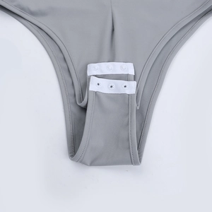 Detail view of the snap button closure on the gray long sleeve bodysuit crotch