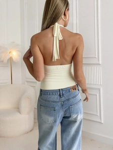 Haut licou dos nu en maille crème pour femme avec un jean bleu clair dans une pièce