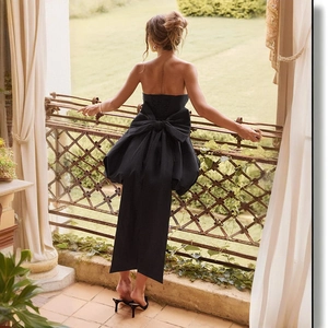 Detail of elegant black strapless dress featuring a large bow and open back design