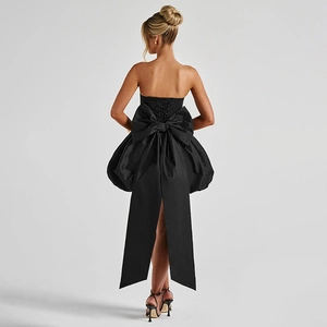 Detail of a black tube dress featuring a large bow and corset-style lace-up back