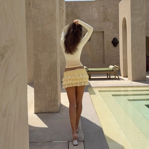 Detail of light yellow slim fit long sleeve top and tiered ruffle mini skirt set