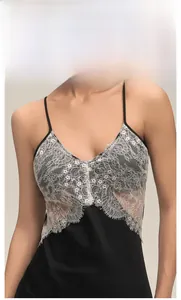 Detail of white lace patchwork on a black satin nightgown with delicate floral patterns