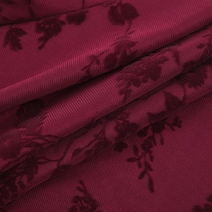 Detail of burgundy mesh fabric with flocked rose patterns and vintage texture