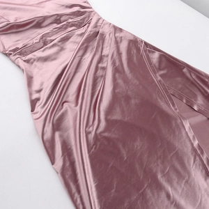 Detailed view of dusty rose satin dress with elegant ruching and side slit texture