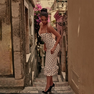 Detailed view of white polka dot dress featuring elegant ruffled hem and slim fit design