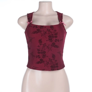 Detail of dark red floral tank top featuring delicate pink silk bows on shoulder straps