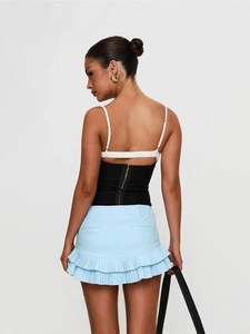 Women's backless halter top with blue tiered mini skirt and black handbag