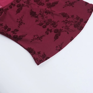 Close-up of burgundy fabric featuring elegant black flocked floral patterns and neat stitching